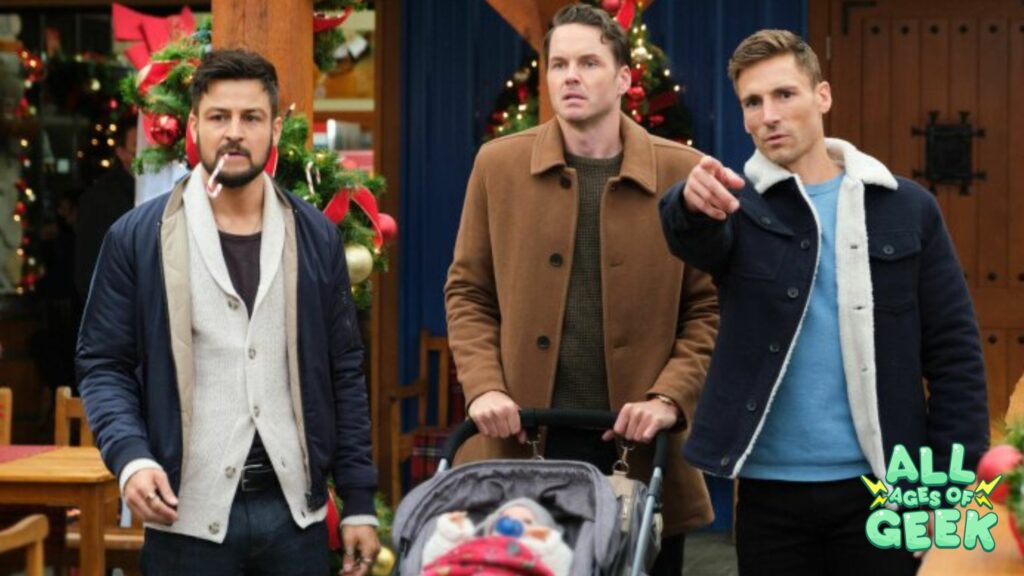 Three men stand outdoors in a festive setting with Christmas decorations in the background. One man has a candy cane in his mouth, another is pushing a baby stroller covered with a red blanket, and the third is pointing at something off-camera. They are all dressed in casual winter clothing and appear to be engaged in a serious conversation. The All Ages of Geek logo is visible in the bottom right corner of the image.