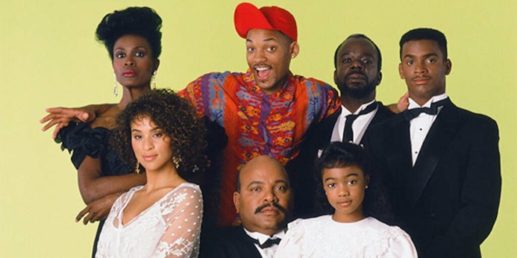 In the image, the main cast of the 90s sitcom "The Fresh Prince of Bel-Air" is featured. At the center, Will Smith, playing the Fresh Prince, stands out with his colorful and flamboyant shirt and a bright red cap, giving a lively and cheerful expression. Surrounding him are his family members, dressed in more formal attire. From left to right, we see Aunt Vivian, standing with a confident and elegant pose, Hilary Banks, seated and looking glamorous in a white outfit, Uncle Phil, seated in front with a stern yet caring expression, Ashley Banks, sitting in front, looking sweet in her white dress, Geoffrey, standing behind in a butler's uniform, with a composed demeanor, and Carlton Banks, standing at the right end, looking sharp in a tuxedo, with his signature confident look. The background is a soft yellow, highlighting the characters and their distinct personalities, capturing the blend of humor, style, and family dynamics that made the show a classic.