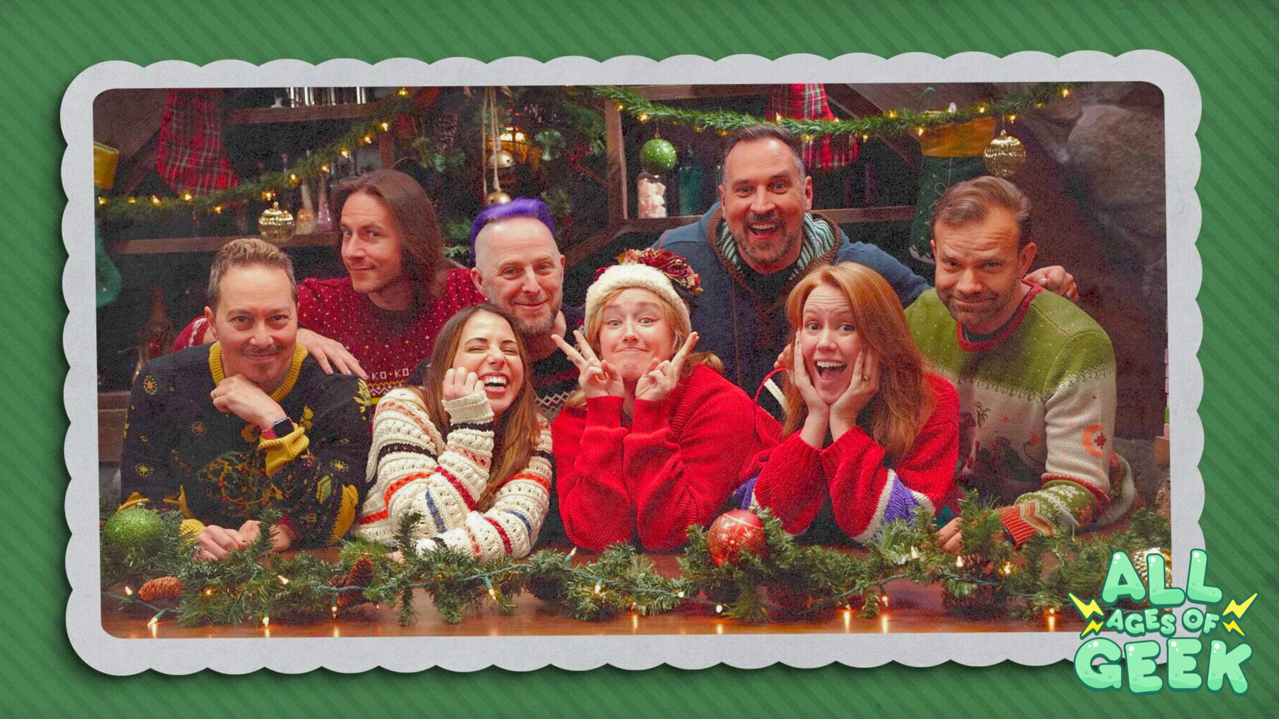 The image features the Critical Role Daggerheart Critmas cast, including Sam Riegel, Laura Bailey, Taliesin Jaffe, Ashley Johnson, Travis Willingham, Marisha Ray, Liam O’Brien, and Game Master Matthew Mercer, posing in a festive setting. They are dressed in holiday sweaters, with playful and joyful expressions, surrounded by Christmas decorations like garlands, ornaments, and lights. The green, textured border of the image gives it the appearance of a holiday card. In the bottom right corner, the All Ages of Geek logo is prominently displayed, indicating that this image is part of their coverage or reaction to the Critical Role Daggerheart Critmas event.