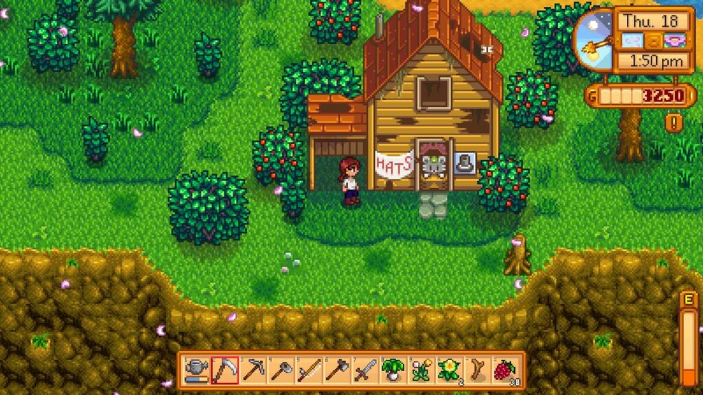 Screenshot from the game Stardew Valley showing a character standing outside a small wooden house labeled 'Hats' with a sign above the door. The house is surrounded by lush green grass and bushes, with some trees and a dirt path nearby. The game interface at the top right displays the in-game time and date as 'Thu. 18,' with the time being 1:50 PM and a balance of 3250 gold. The toolbar at the bottom of the screen shows various tools and items, including a watering can, hoe, pickaxe, and seeds. Used for New Jersey Video Game Ideas Article.