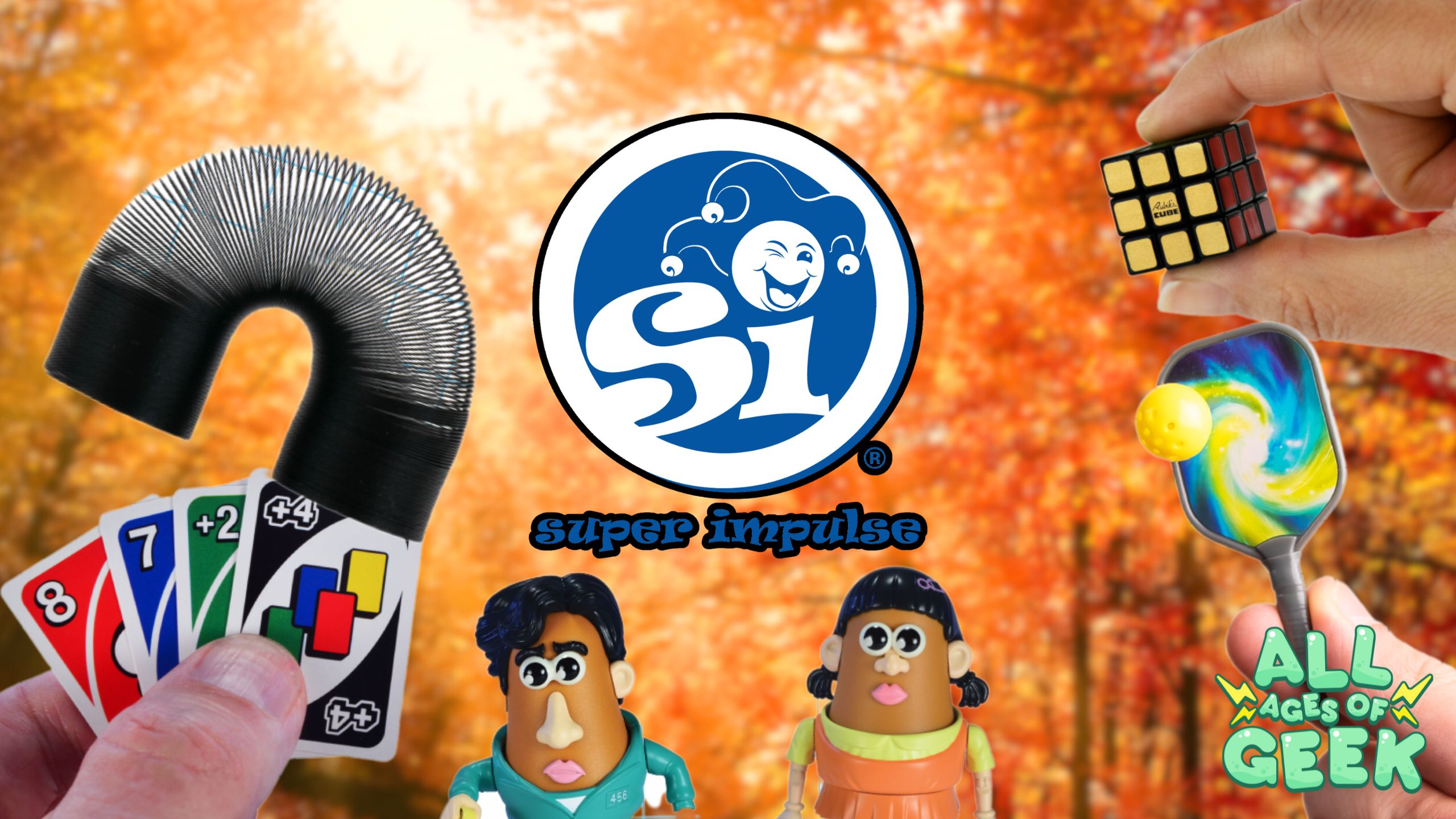 Super Impulse logo with various toys showcased, including a Slinky, UNO cards, a Rubik's cube, and mini versions of Mr. and Mrs. Potato Head. The background features a fall scene with orange foliage, highlighting the brand's Fall Haul campaign