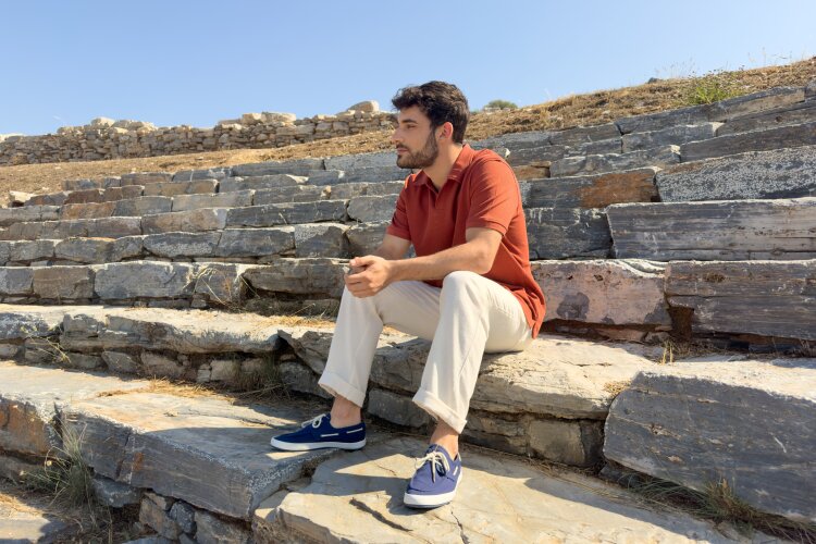 Theo sitting alone on the ancient amphitheater steps, deep in thought.