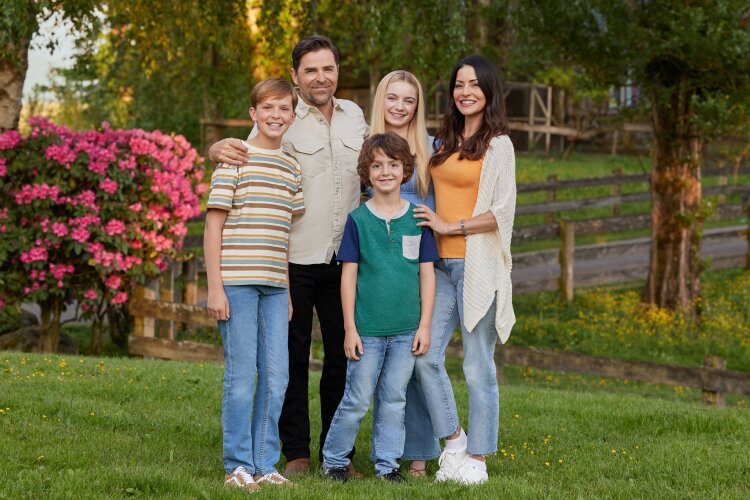 A family of five standing together outdoors, smiling for a group photo. From Hallmark's "Big Sky River: The Bridal Path" ​