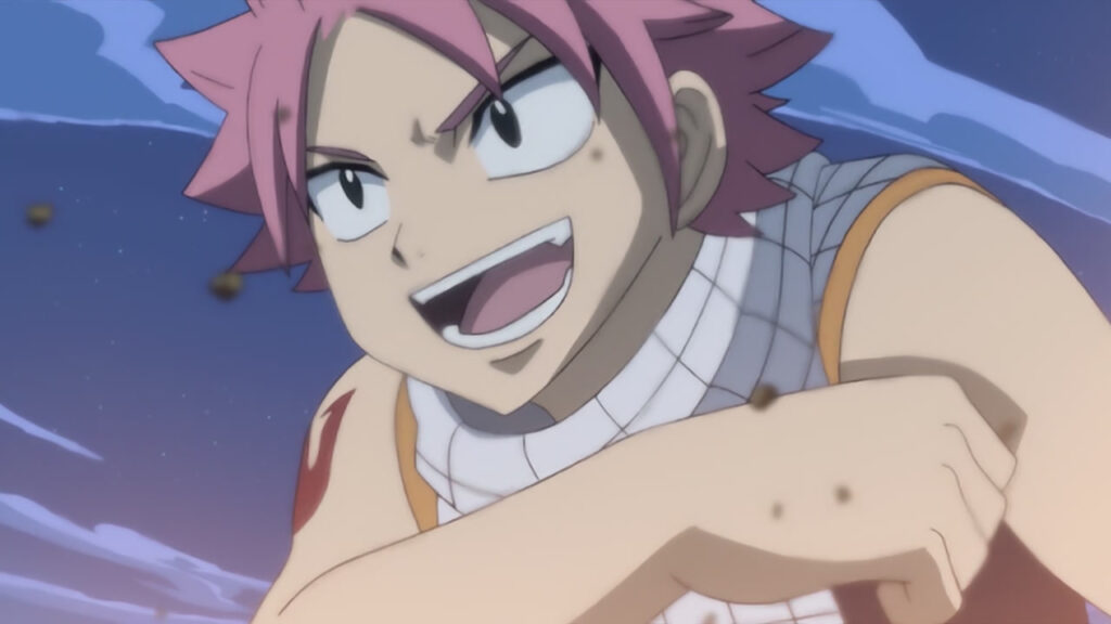 Natsu grinning with a winning look, fist pressed against his arm as a fire glow sparks in the foreground.