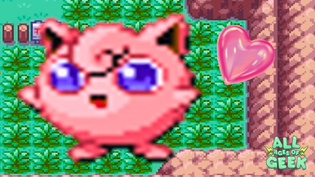 Pixelated image of Jigglypuff, a pink, round Pokémon with big blue eyes and a happy expression, from the Pokémon series. Jigglypuff is set against a pixelated background of green grass and a dirt path. A shiny pink heart is positioned to the right of Jigglypuff. The All Ages of Geek logo is in the bottom right corner.