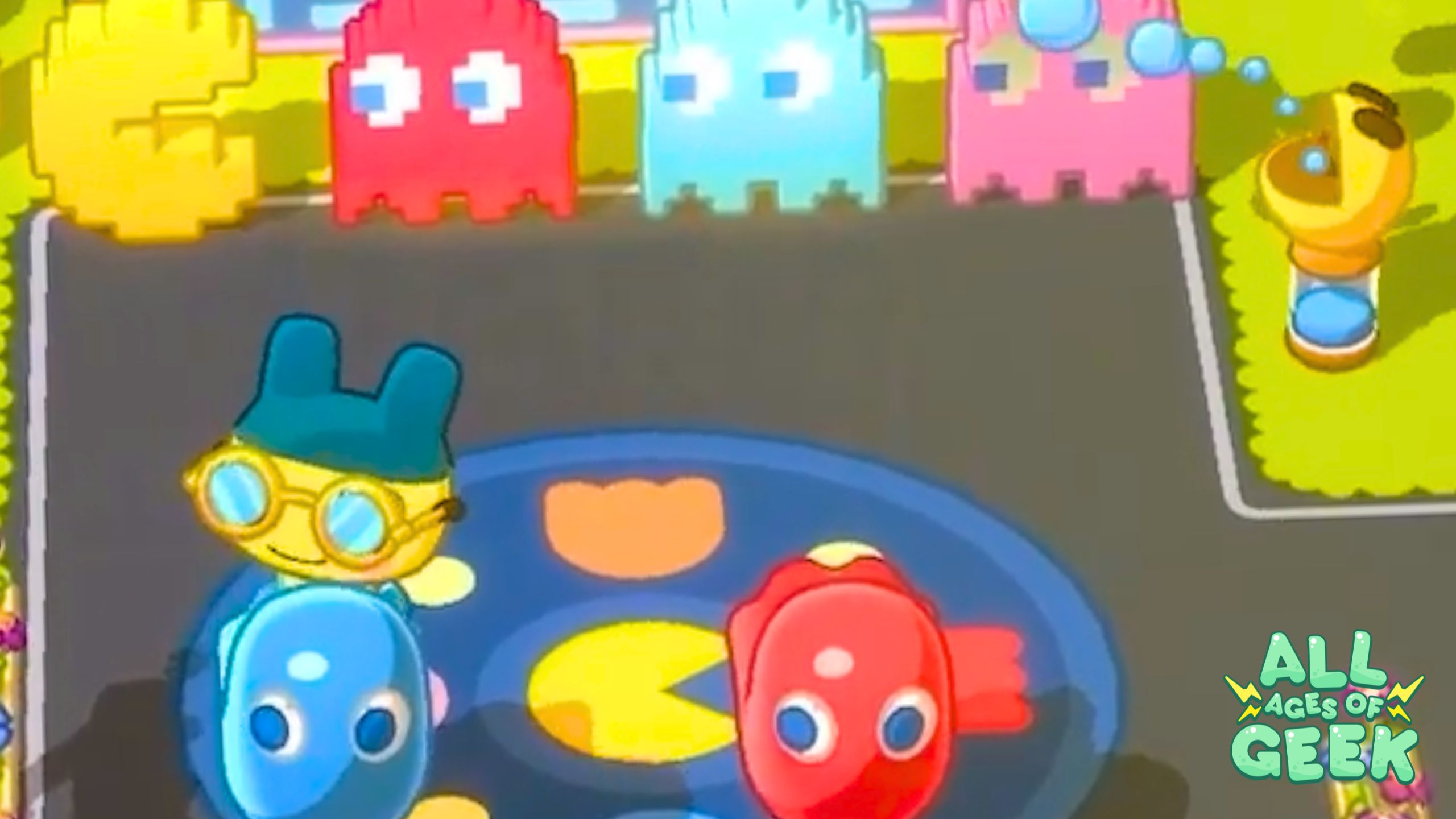 Tamagotchi characters enjoying the PAC-MAN crossover event in Tamagotchi Adventure Kingdom, featuring colorful PAC-MAN ghosts and a vibrant game area with the All Ages of Geek logo in the corner.