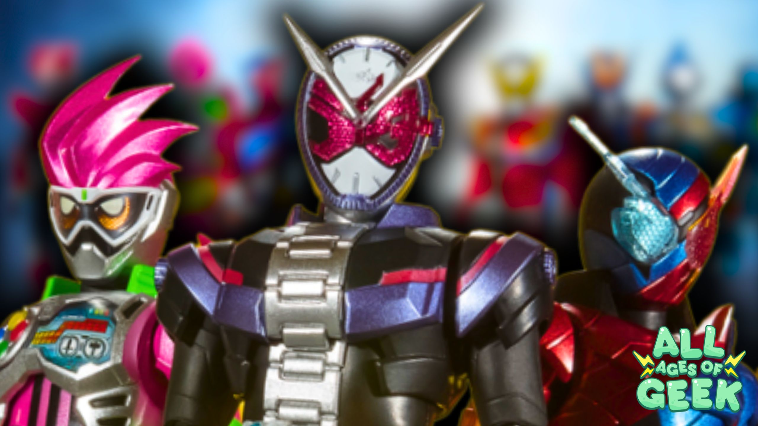 Three Kamen Rider characters are prominently featured in the foreground with vibrant colors. The character on the left has bright pink hair and a futuristic mask, the center character has a clock-themed helmet with red eyes, and the character on the right sports a blue and red helmet with a unique design. In the background, blurred figures of more Kamen Riders can be seen. The 'All Ages of Geek' logo is positioned at the bottom right corner.