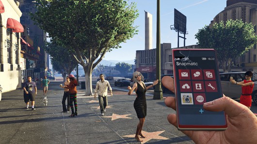 This image from Grand Theft Auto V shows the three main characters—Trevor, Michael, and Franklin—huddled around a smartphone. Each of them is engrossed in whatever they're looking at, likely related to a mission or heist they're planning. Trevor, with his characteristic wild appearance, is shirtless and wearing aviator sunglasses. Michael, dressed in his usual suit, looks calm but focused, as if contemplating the situation. Franklin, in a black varsity jacket, leans in closely, also paying full attention.

The background shows an industrial, worn-down environment typical of GTA V, with old tires, cracked roads, and a rundown building with a "Highway Clearance" sign. The scene gives off a feeling of intense planning or coordination between the characters, capturing a key moment in the game where the trio is probably about to embark on another one of their high-stakes, criminal adventures.