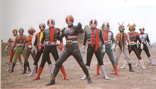 A group of ten Kamen Riders from the Showa era, all wearing distinctive bug-eyed helmets, colored armor, and red scarves, stand in a heroic formation. They are positioned on barren ground with a clear sky backdrop, showcasing various designs from different generations of Kamen Riders, including Kamen Rider V3, Kamen Rider X, and Kamen Rider Amazon. The lead Rider is in the front, raising one hand in a commanding pose, while the others stand ready behind him.