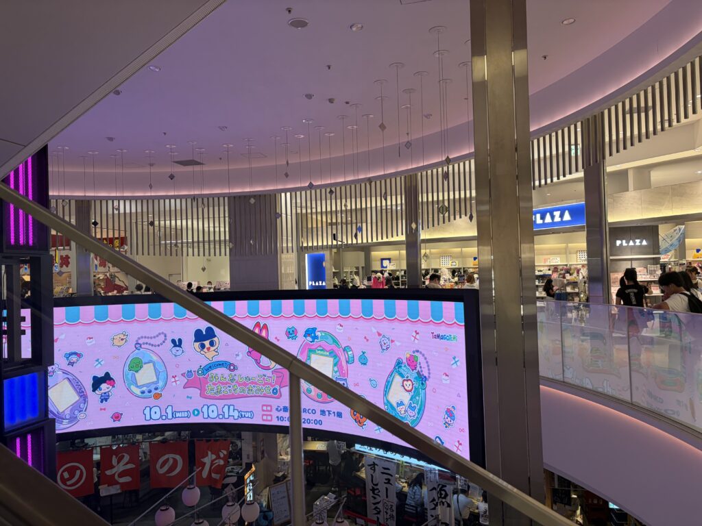 Bright LED screen at Shinsaibashi PARCO mall advertising the Tamagotchi pop-up store event with cute characters and event dates.
