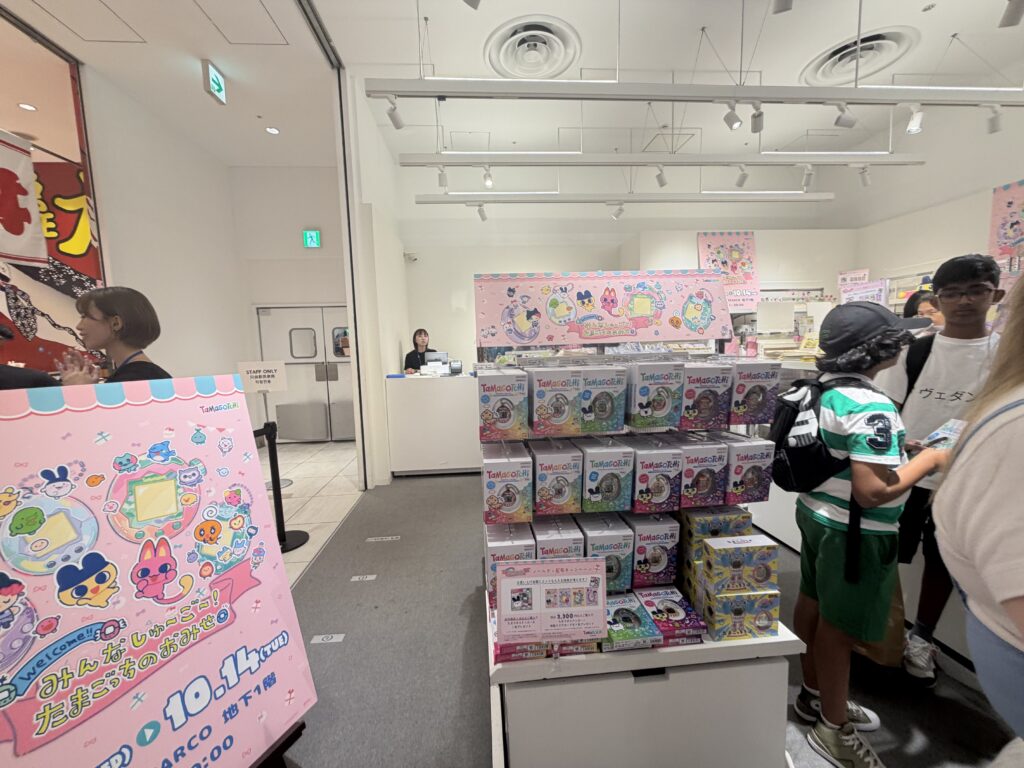 Display shelves packed with Tamagotchi-themed notebooks, mugs, stationery, and colorful accessories neatly organized.