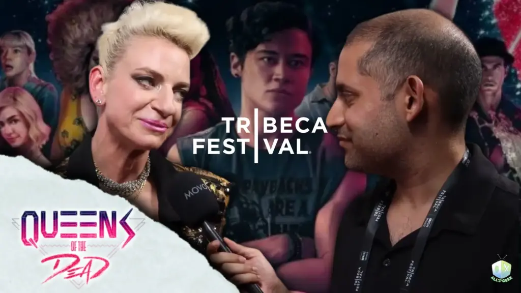 Interview at the Tribeca Film Festival featuring Tina Romero in a black and gold outfit speaking into a microphone held by All Ages of Geek's Mufsin wearing a Tribeca badge, with the Queens of the Dead logo and a collage of cast members in the background, highlighting the film’s festival premiere.