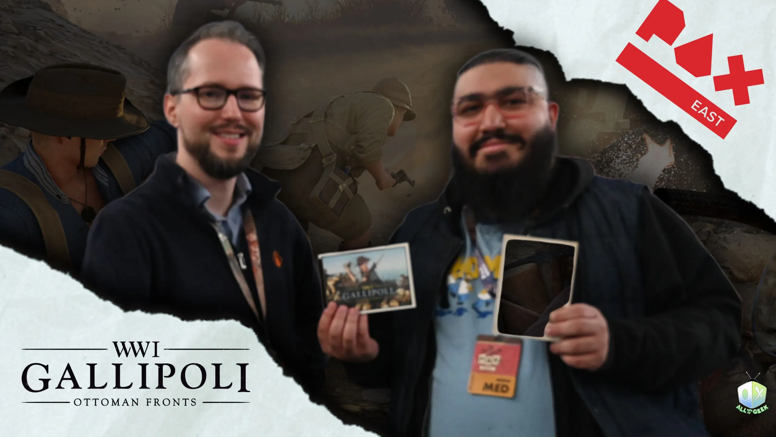 Two men at PAX East pose for a photo while holding Gallipoli: Ottoman Fronts materials, with WW1 gameplay imagery in the background and event branding visible.